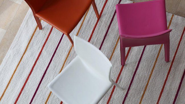 Bunte Stühle auf gestreiftem Teppich von oben gesehen