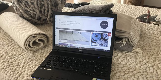 Laptop zeigt Teppich-Onlineshop auf Bettdecke